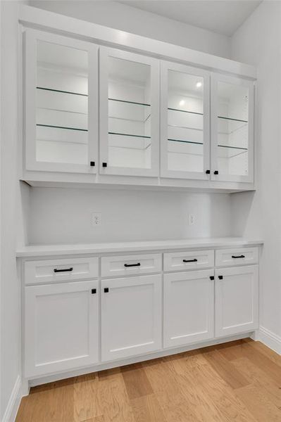 Bar with light hardwood / wood-style floors and white cabinetry