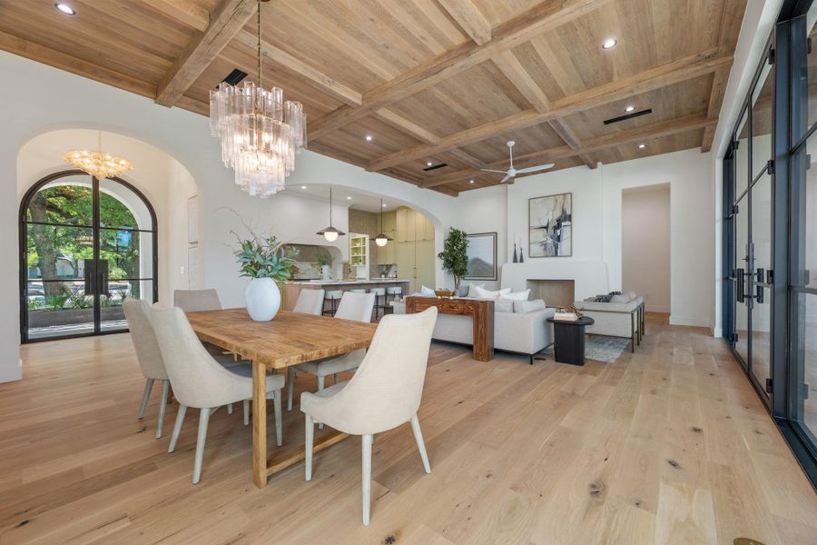 Rich wood plank flooring and an intricate paneled ceiling define this open-plan dining area.