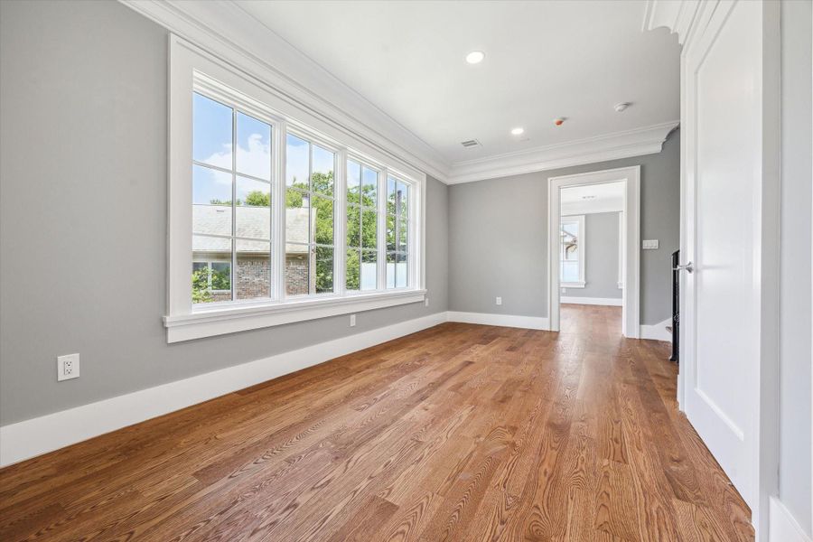 This beautiful space is the second floor landing with hardwood floors, large windows, and recessed lighting. Fresh gray walls and white trim create a modern, airy feel. Ideal for a study space, game playing or cozy sitting area.