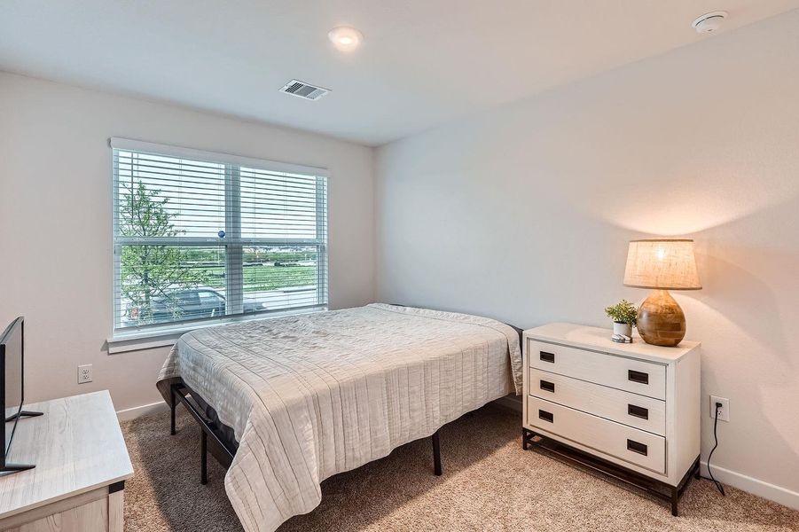 Bedroom with visible vents, light colored carpet, and baseboards