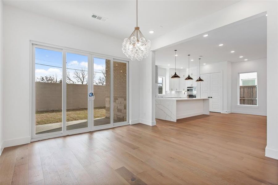 Unfurnished living room featuring a healthy amount of sunlight, a notable chandelier, and light hardwood / wood-style flooring