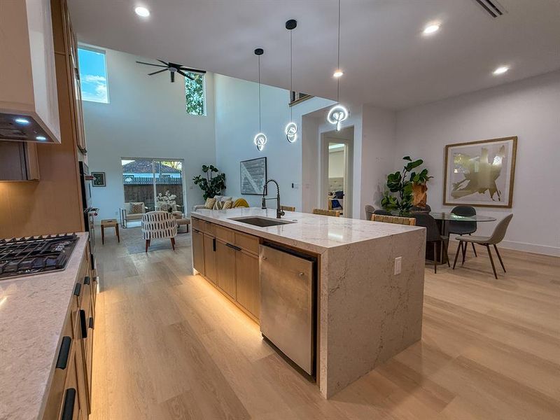 Kitchen featuring recessed lighting, hanging light fixtures, light wood-style flooring, light stone countertops, and stainless steel appliances