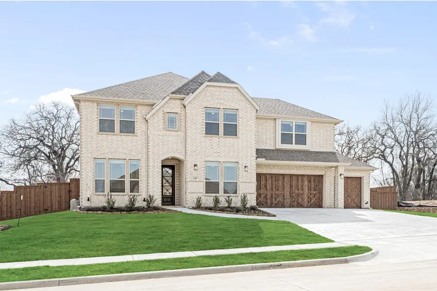 Two-story brick home with arched entry, three-car garage, and manicured front lawn