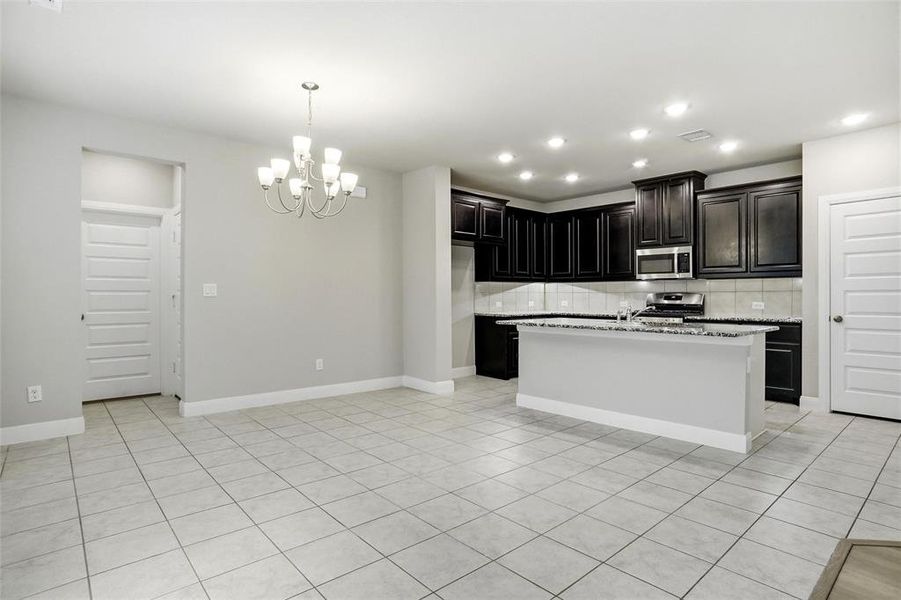 7 ft breakfast bar, cabinets accent by white quartz counters and brick tile backsplash, stainless appliances, walk in pantry, doorway into separate utility on left