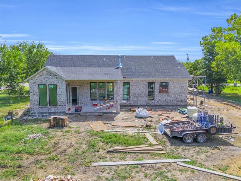 Rear view of house with a shingled roof, a patio, and brick siding Rear view of house with a shingled roof, a patio, and brick siding