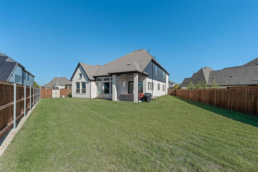 Rear view of house with a patio, a fenced backyard, brick siding, and a shingled roof