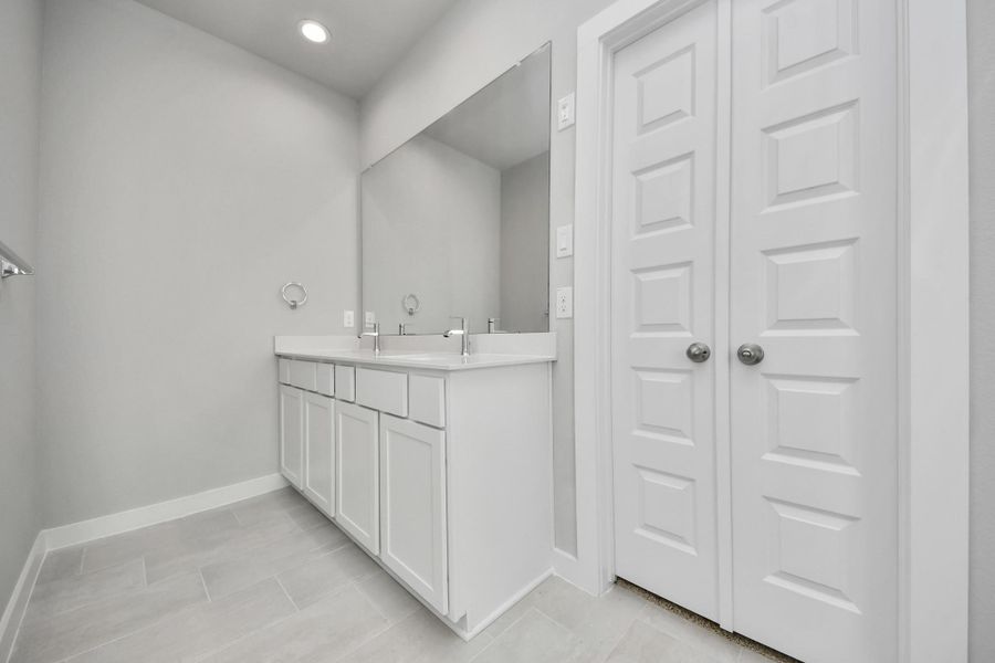 Escape to a spa-like oasis in this primary bathroom. Enjoy a walk-in shower with tile surround, a separate garden tub with custom detailing, and an elegant vanity featuring light countertops, modern hardware, and beautiful vanity lights. Experience luxury and relaxation in every detail. Sample photo of completed home with similar floor plan. Actual colors and selections may vary.