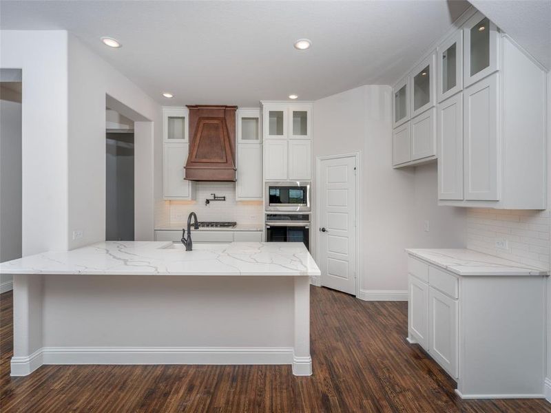 Kitchen with decorative backsplash, white cabinets, light stone counters, and recessed lighting Kitchen with decorative backsplash, white cabinets, light stone counters, and recessed lighting