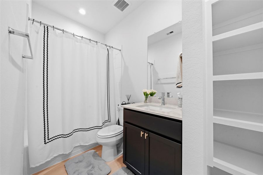 The third bathroom showcases a streamlined vanity with a light countertop, paired with a versatile shower-tub combo and thoughtfully designed open shelving. The third bathroom showcases a streamlined vanity with a light countertop, paired with a versatile shower-tub combo and thoughtfully designed open shelving.