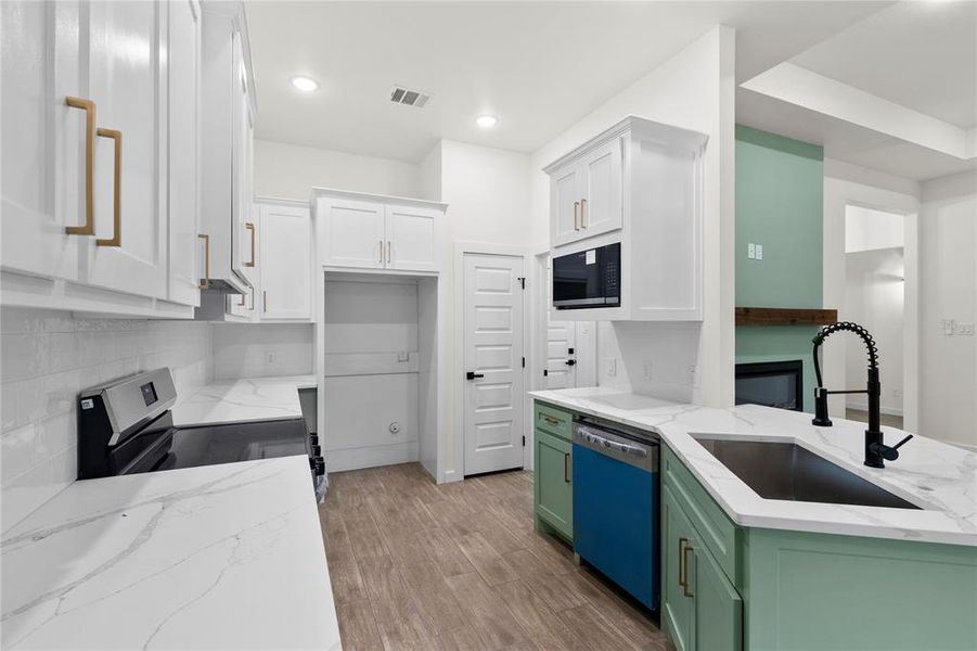 Modern kitchen featuring white shaker cabinetry with gold-finish hardware, quartz countertops, and a subway tile backsplash