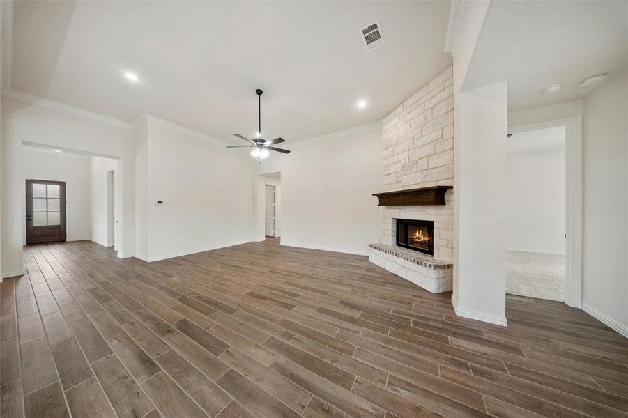 Unfurnished living room featuring a fireplace, dark wood-style flooring, a ceiling fan, ornamental molding, and recessed lighting