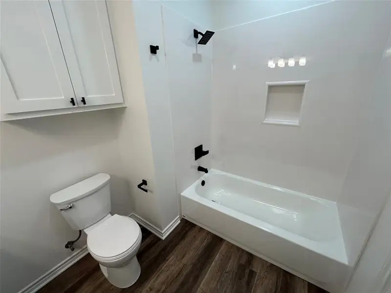 Full bath featuring dark wood finished floors and  shower combination