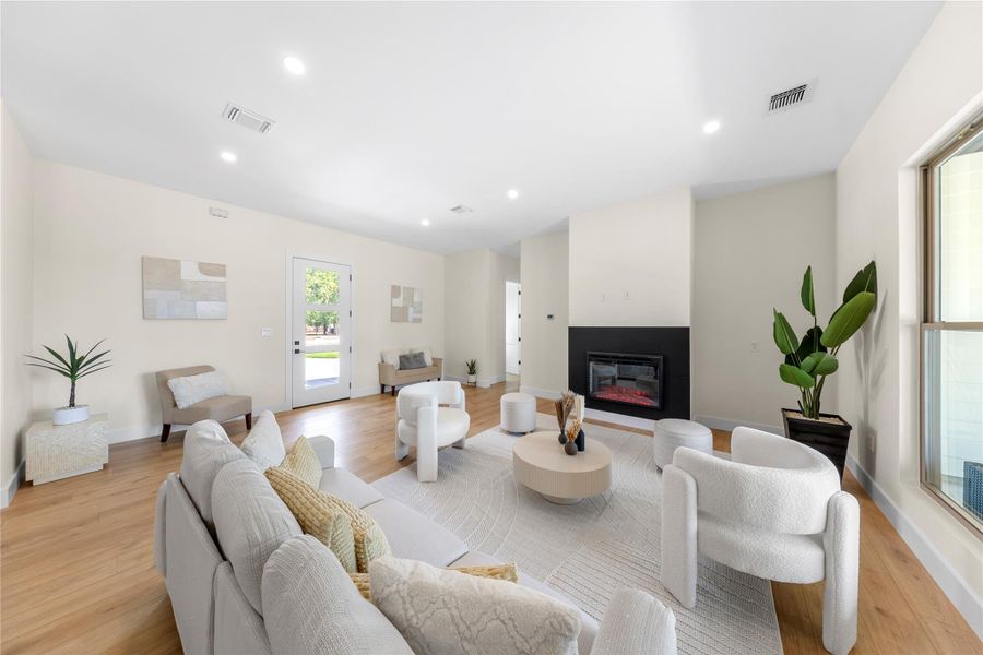 Living room featuring recessed lighting, a glass covered fireplace, and light wood finished floors Living room featuring recessed lighting, a glass covered fireplace, and light wood finished floors