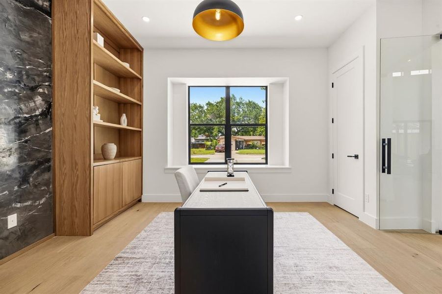 Built-in wood shelving with lower cabinetry, a dark accent wall, and wood-finish flooring