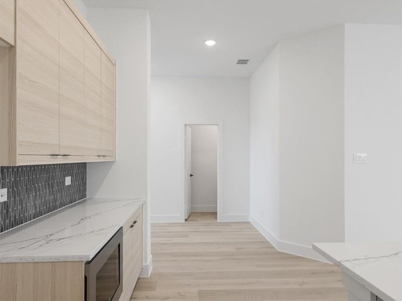 Bar featuring light brown cabinetry, light stone countertops, light wood-style flooring, tasteful backsplash, and recessed lighting Bar featuring light brown cabinetry, light stone countertops, light wood-style flooring, tasteful backsplash, and recessed lighting