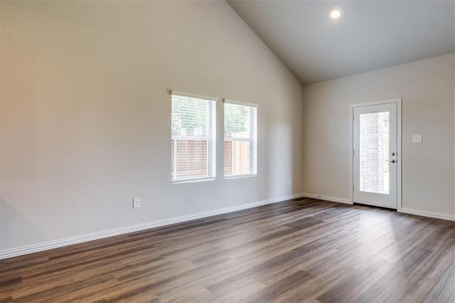 Empty room featuring hardwood / wood-style flooring and high vaulted ceiling