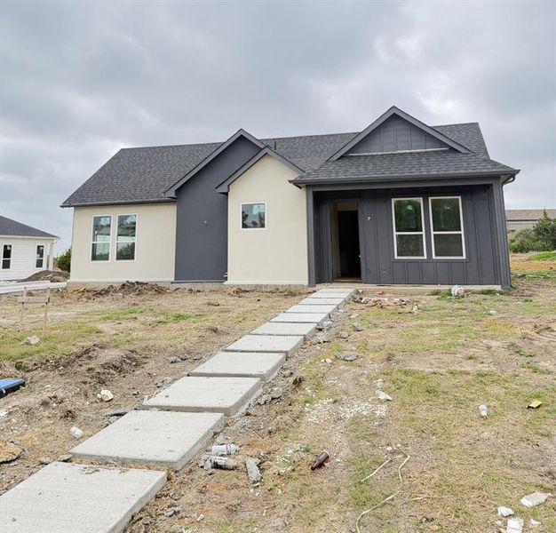 View of front of home with roof with shingles and board and batten siding