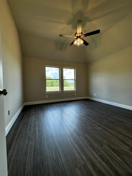 Empty room featuring dark hardwood / wood-style floors, ceiling fan, and lofted ceiling