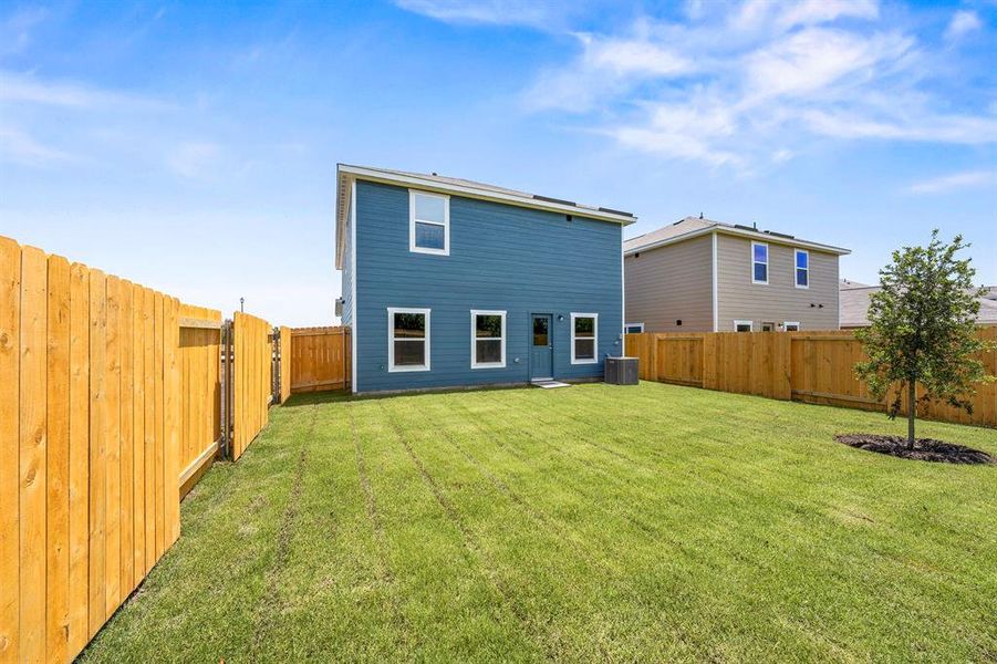 Back of property featuring central AC unit and a lawn