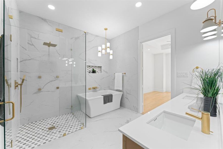 Full bath with a chandelier, a freestanding bath, double vanity, light marble finish floors, and a marble finish shower