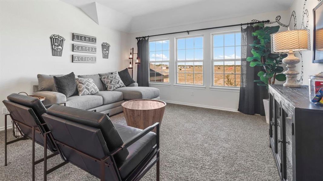 Carpeted living area featuring a vaulted ceiling and three large windows