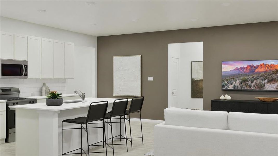 Kitchen with appliances with stainless steel finishes, white cabinetry, backsplash, a center island with sink, and a breakfast bar area Kitchen with appliances with stainless steel finishes, white cabinetry, backsplash, a center island with sink, and a breakfast bar area