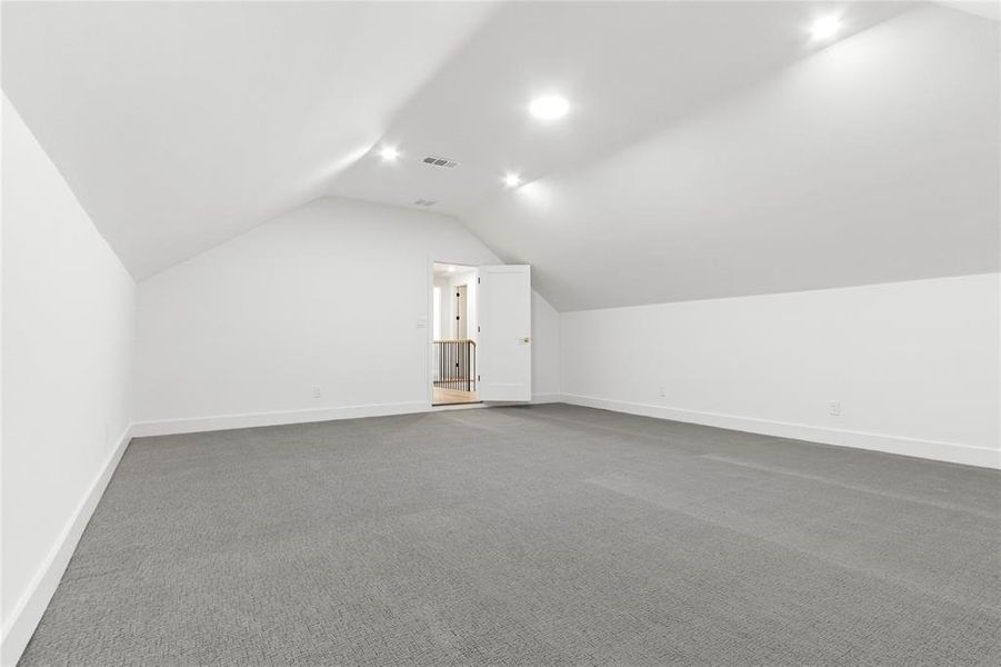 Bonus room with lofted ceiling and carpet