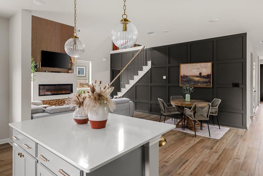 Kitchen featuring light wood finished floors, a center island, a glass covered fireplace, open floor plan, and hanging light fixtures