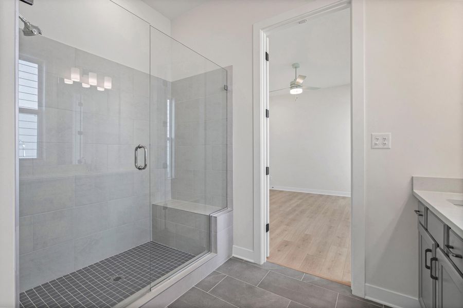 Glass-enclosed shower with a built-in bench and tiled floor