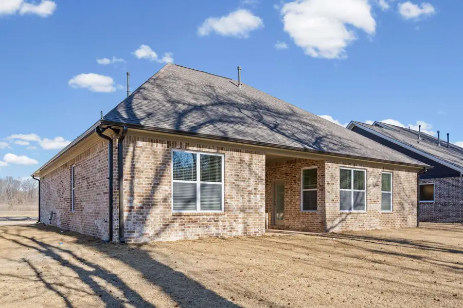 Back of property featuring a patio, brick siding, and a shingled roof