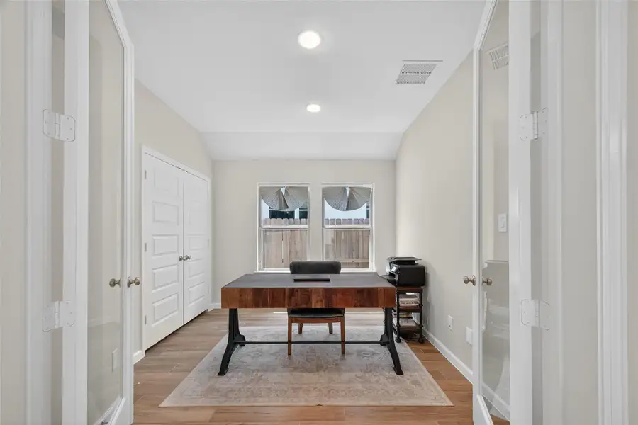 This is a bright, well-lit office with double glass doors, featuring a wooden desk, neutral walls, and hardwood floors. It can also be utilized as a game room. There's storage with a closet and a window providing natural light. This is a bright, well-lit office with double glass doors, featuring a wooden desk, neutral walls, and hardwood floors. It can also be utilized as a game room. There's storage with a closet and a window providing natural light.