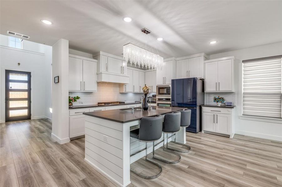 Welcome through the modern front door into a space with vaulted ceilings. The luxury kitchen boasts stainless steel appliances, a large center island with breakfast bar, and flows seamlessly into the spacious dining area. Bright white cabinetry, abundant natural light from multiple windows, and a combination of elegant fixtures and recessed lighting make this the heart of the home! Welcome through the modern front door into a space with vaulted ceilings. The luxury kitchen boasts stainless steel appliances, a large center island with breakfast bar, and flows seamlessly into the spacious dining area. Bright white cabinetry, abundant natural light from multiple windows, and a combination of elegant fixtures and recessed lighting make this the heart of the home!