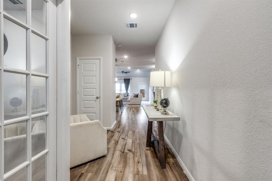 Hall featuring light wood-type flooring, recessed lighting, and a textured wall