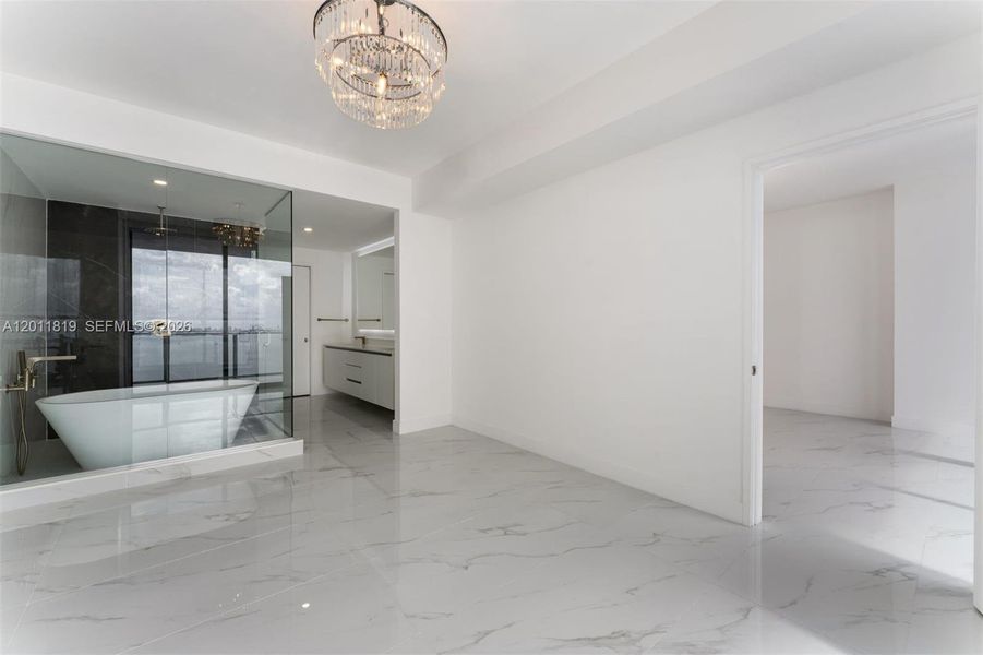 Spa-inspired primary bathroom featuring dual vanities, a deep soaking tub, a frameless glass rainfall shower, and designer porcelain tile throughout.