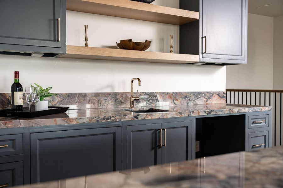 The wet bar has a dynamic Marbella quartzite slab counter. The black quartz sink and Brizo Odin bar faucet will aid you in preparing snacks or cocktails. The opening will house a beverage cooler (to be installed). The wet bar has a dynamic Marbella quartzite slab counter. The black quartz sink and Brizo Odin bar faucet will aid you in preparing snacks or cocktails. The opening will house a beverage cooler (to be installed).