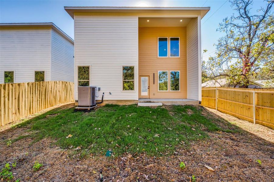 Rear view of house with a yard and central AC