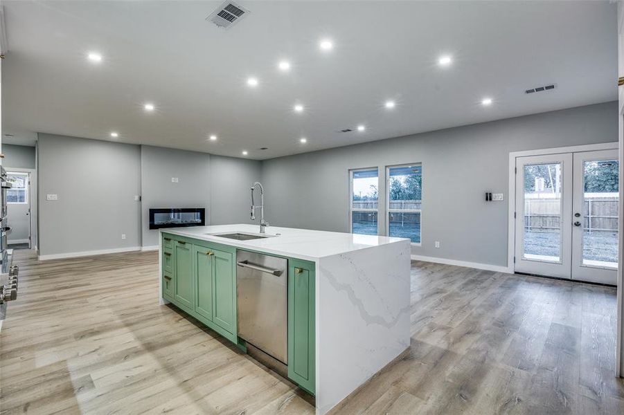 Kitchen featuring dishwasher, french doors, a center island with sink, green cabinets, and sink