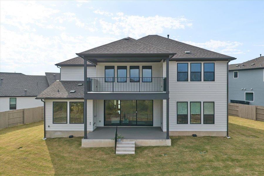 Back of house with a fenced backyard, a patio, roof with shingles, and a balcony Back of house with a fenced backyard, a patio, roof with shingles, and a balcony