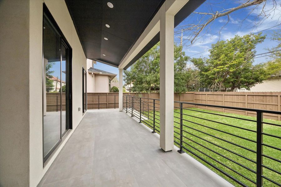 The wide tiled covered back porch runs along the back of the house.
