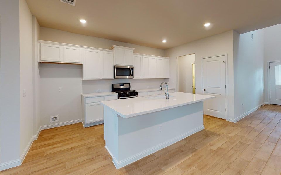 Kitchen featuring white cabinets, stainless steel appliances, a kitchen island with sink, light wood-type flooring, and recessed lighting
