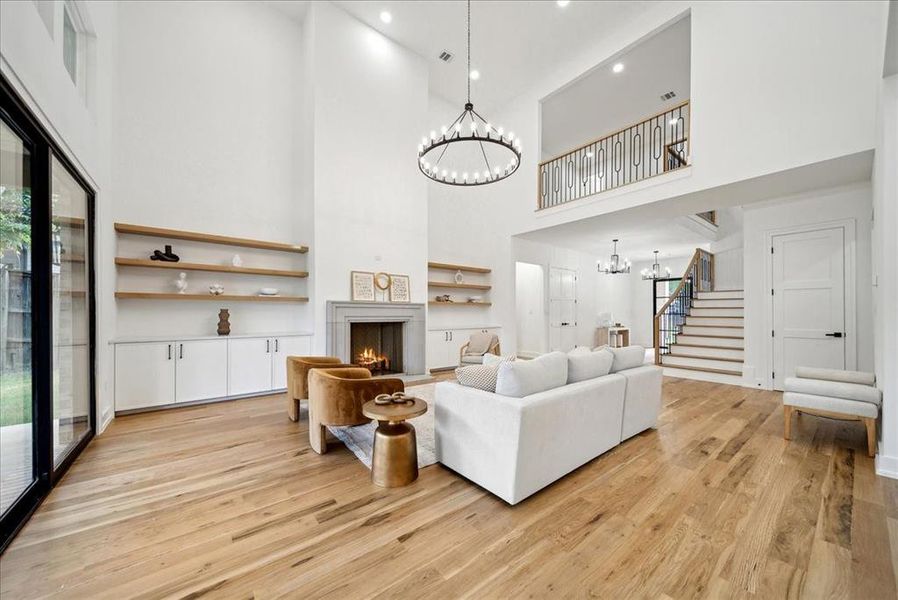 Living room featuring a high ceiling, hardwood flooring, and a notable chandelier