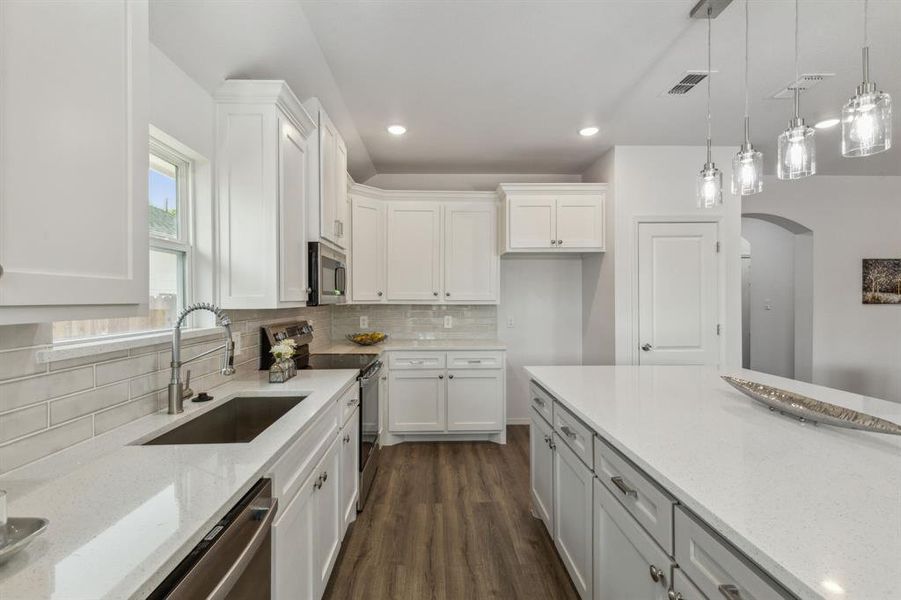 Kitchen with stainless steel appliances, sink, decorative light fixtures, decorative backsplash, and dark hardwood / wood-style floors