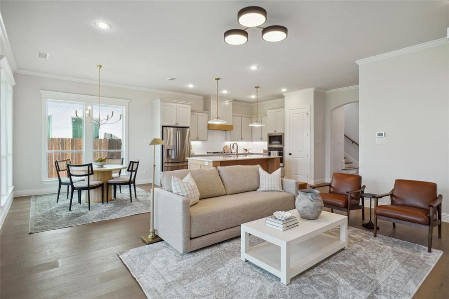 Living room with an inviting chandelier, light hardwood / wood-style flooring, sink, and ornamental molding