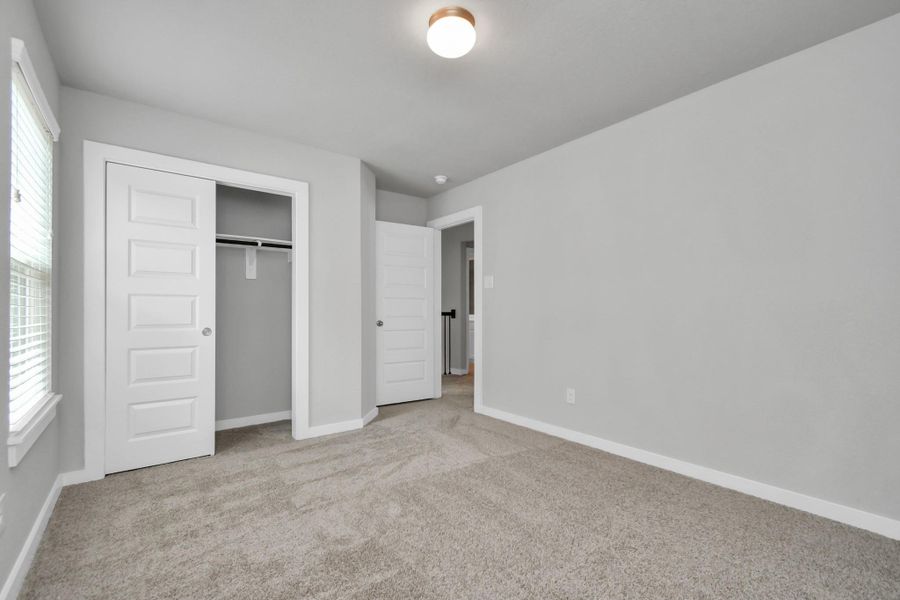 generously sized secondary bedrooms, showcasing 5-panel doors with modern hardware, large windows adorned with privacy blinds, and spacious closets boasting sleek and contemporary finishes. Sample photo of completed home with similar floor plan. Actual colors and selections may vary.