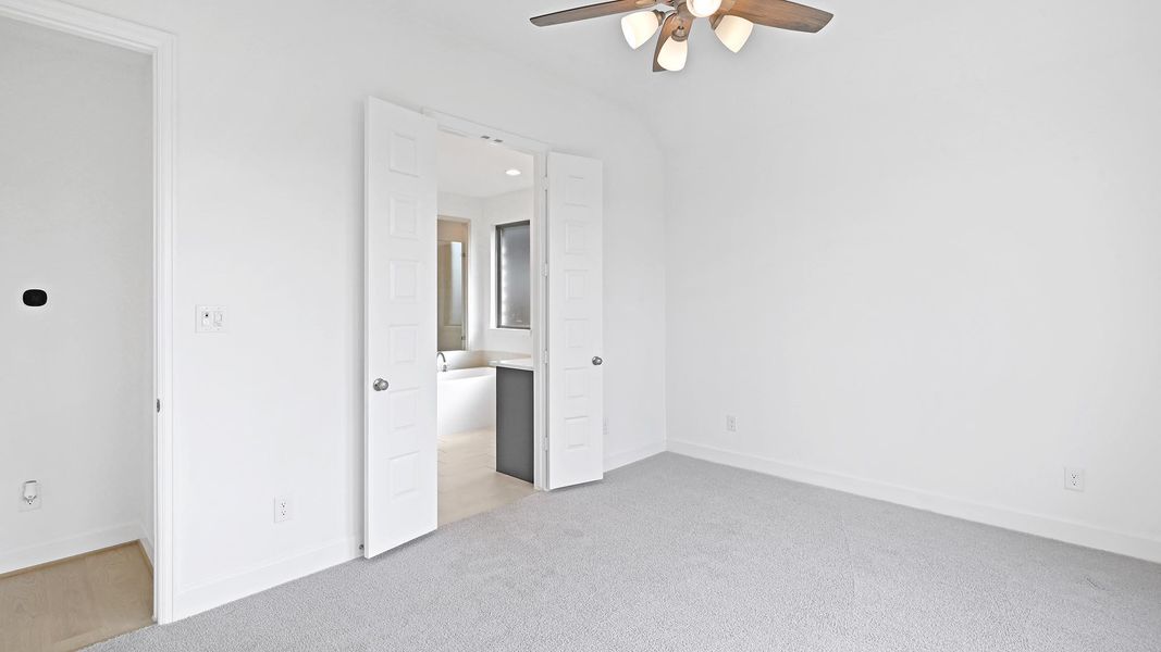 Unfurnished bedroom featuring light carpet, connected bathroom, and a ceiling fan