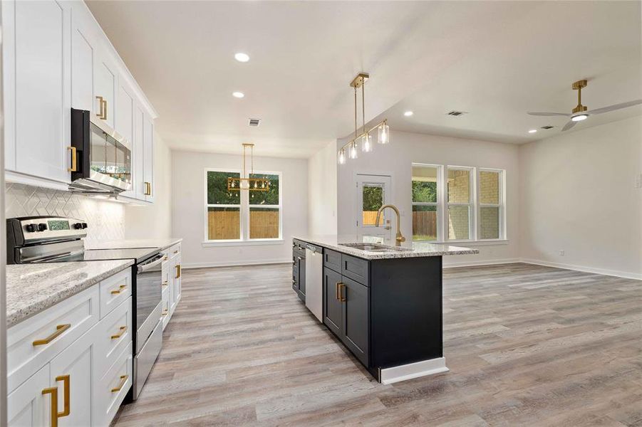 Kitchen with white cabinetry, stainless steel appliances, decorative light fixtures, recessed lighting, and backsplash Kitchen with white cabinetry, stainless steel appliances, decorative light fixtures, recessed lighting, and backsplash