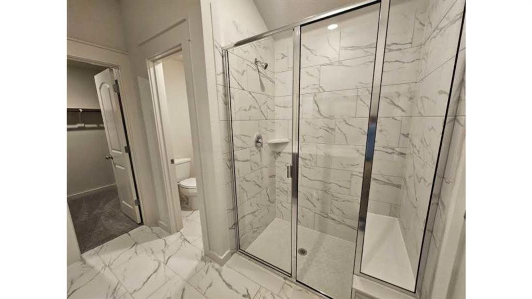 Walk-in shower with clear glass enclosure, integrated bench seating, and a built-in shower niche Walk-in shower with clear glass enclosure, integrated bench seating, and a built-in shower niche