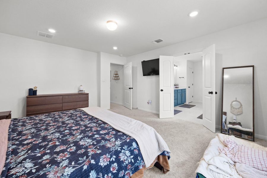 Spacious bedroom featuring light-toned carpeting and recessed lighting