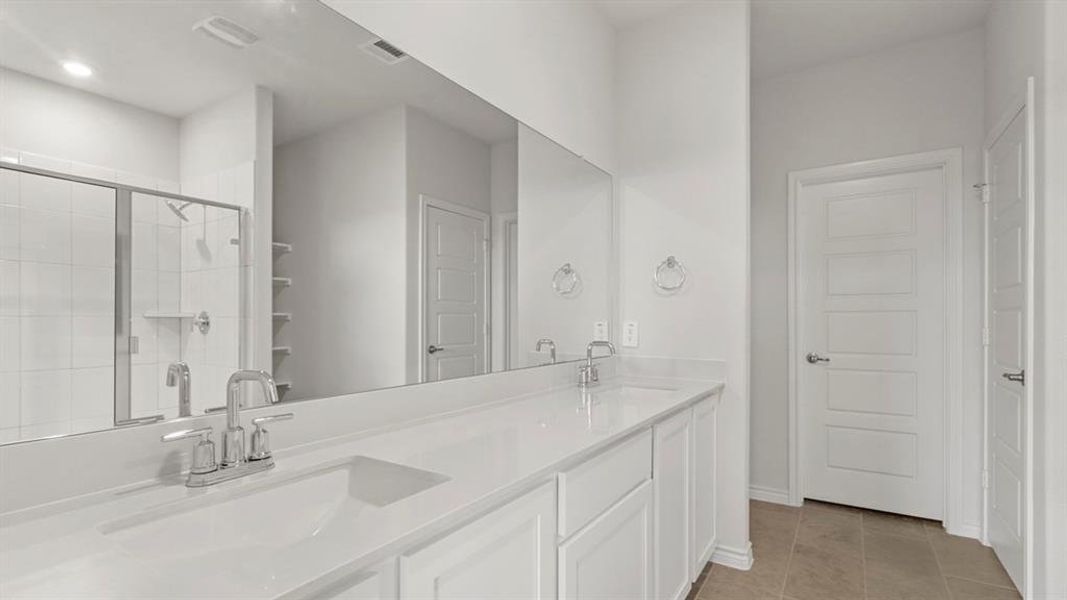 Bathroom with double vanity, a shower stall, and light tile patterned flooring