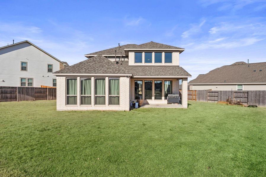 Rear view of property with roof with shingles, brick siding, a patio, and a fenced backyard